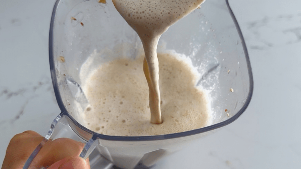 A top-down view of frothy, creamy cashew milk inside a blender.
