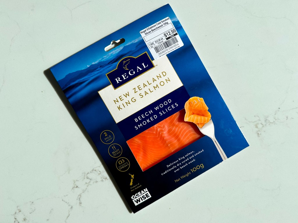 A packet of Regal New Zealand King Salmon Beech Wood Smoked Slices on a white marble bench top.