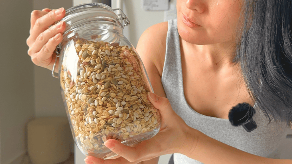 Holding a 1.8L clear IKEA Korken glass jar filled to the top with toasted muesli.